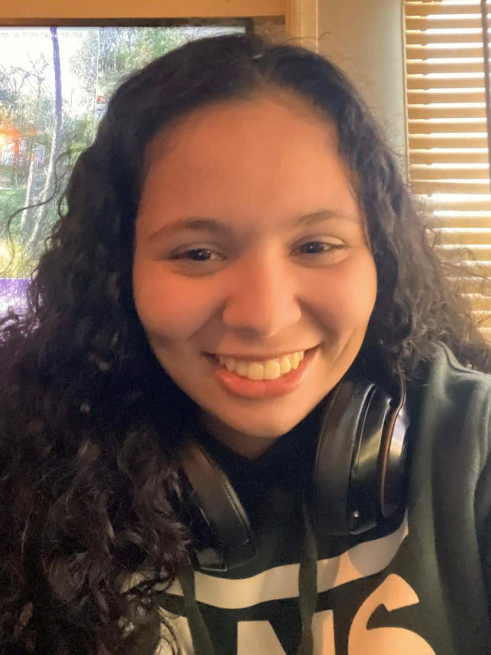 photo of a young woman with curly hair smiling into the camera